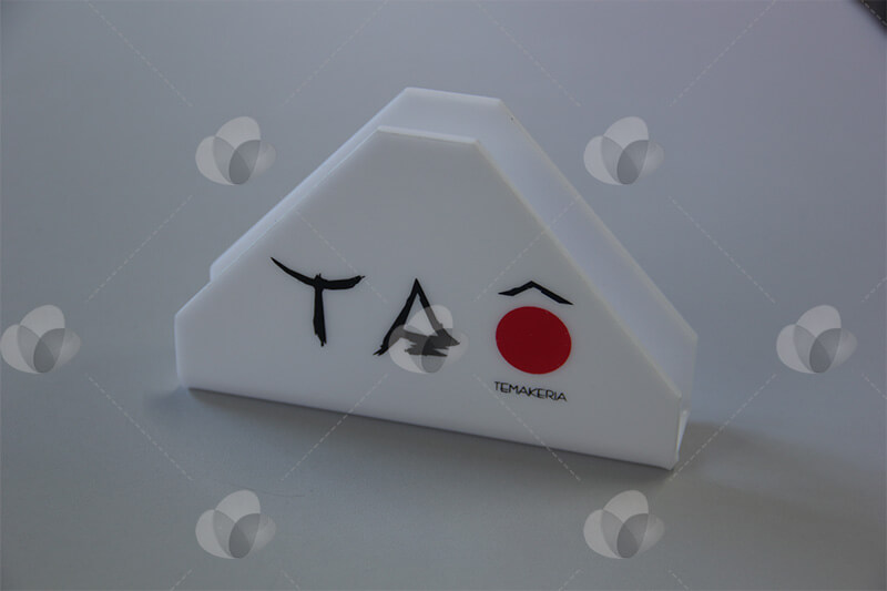 Porta guardanapos em acrílico no formato triangular personalizado com serigrafia reproduzindo a marca do restaurante Taô